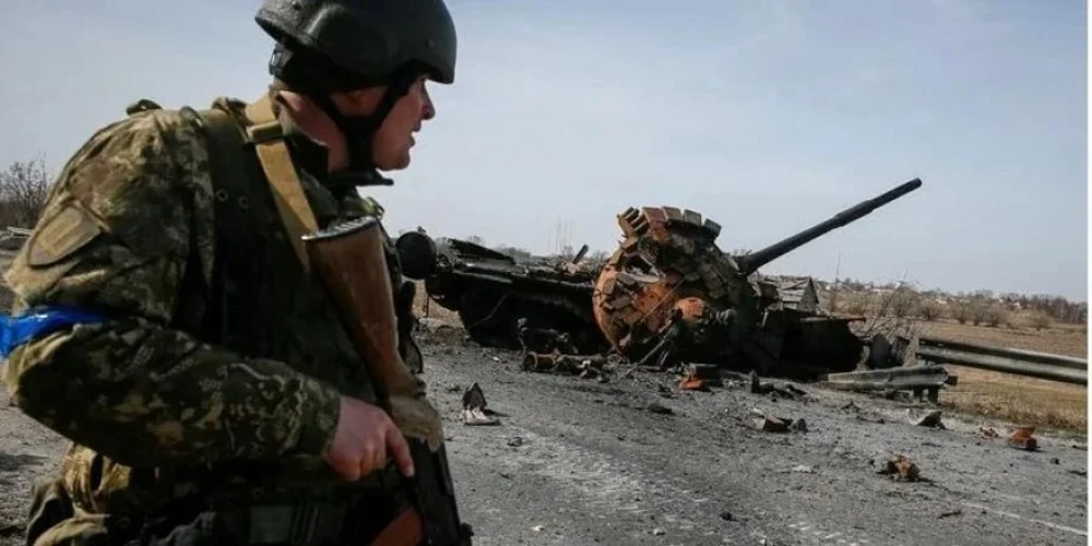 Український військовий біля уламків російського танка у Київській області 28 березня 2022 року (фото REUTERS/Gleb Garanich)