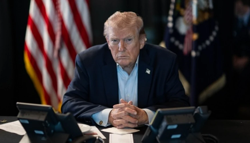 Дональд Трамп під час спілкування з журналістами на тлі прапорів США